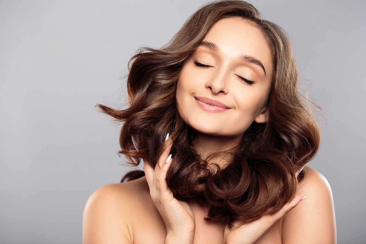 Brunette girl with healthy curly hair and natural make up . Beau