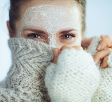 elegant woman with white facial mask hiding behind clothes