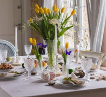 Easter festive spring table setting decoration, eggs in nest, fresh yellow tulips, marshmallows, selective focus banner