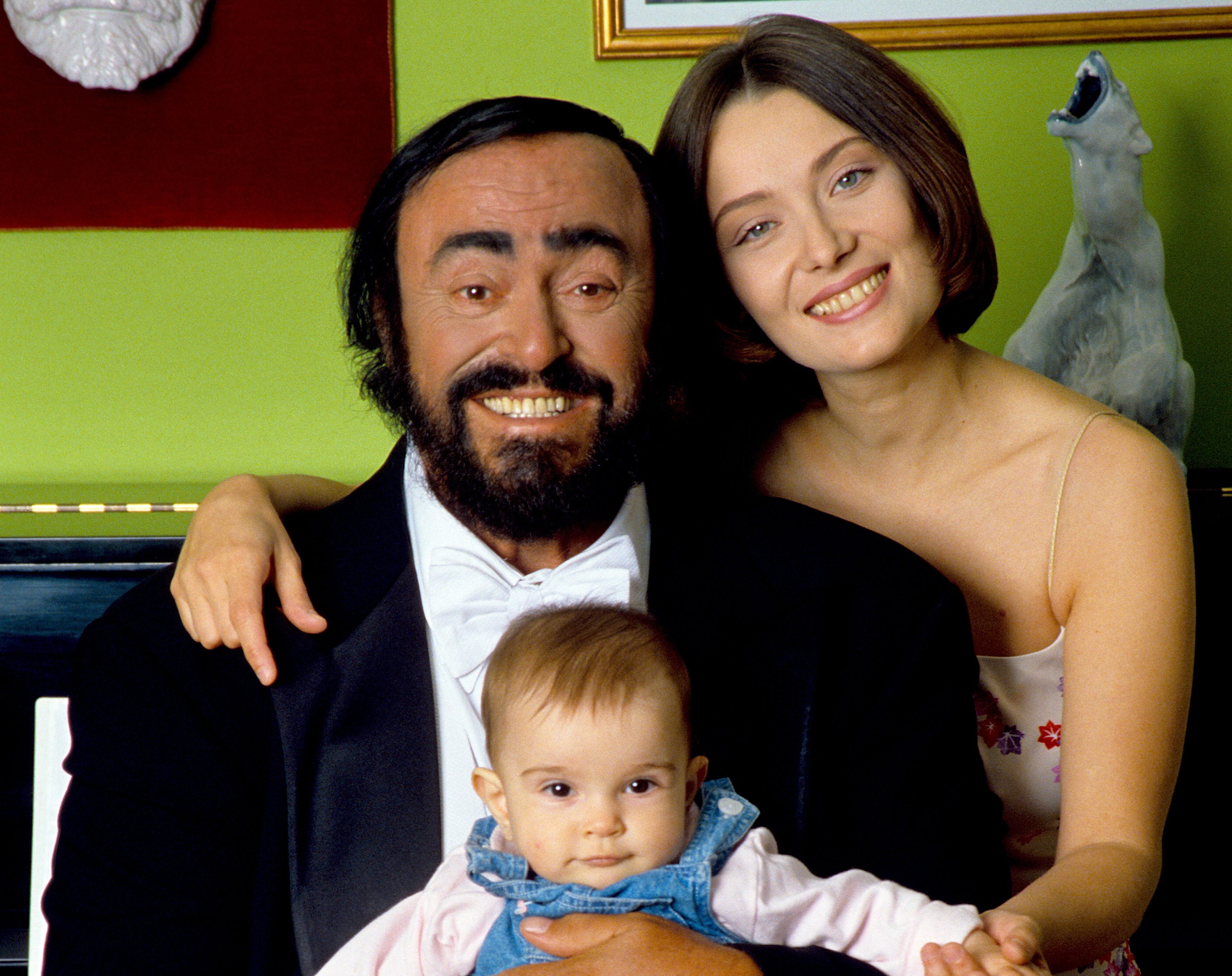 Luciano Pavarotti poses holding his daughter Alice, with his wife Nicoletta Mantovani
