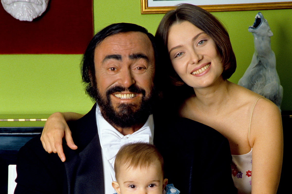Luciano Pavarotti poses holding his daughter Alice, with his wife Nicoletta Mantovani