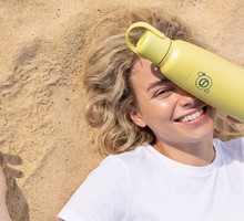 Młoda kobieta na plaży z butelką fizz&go