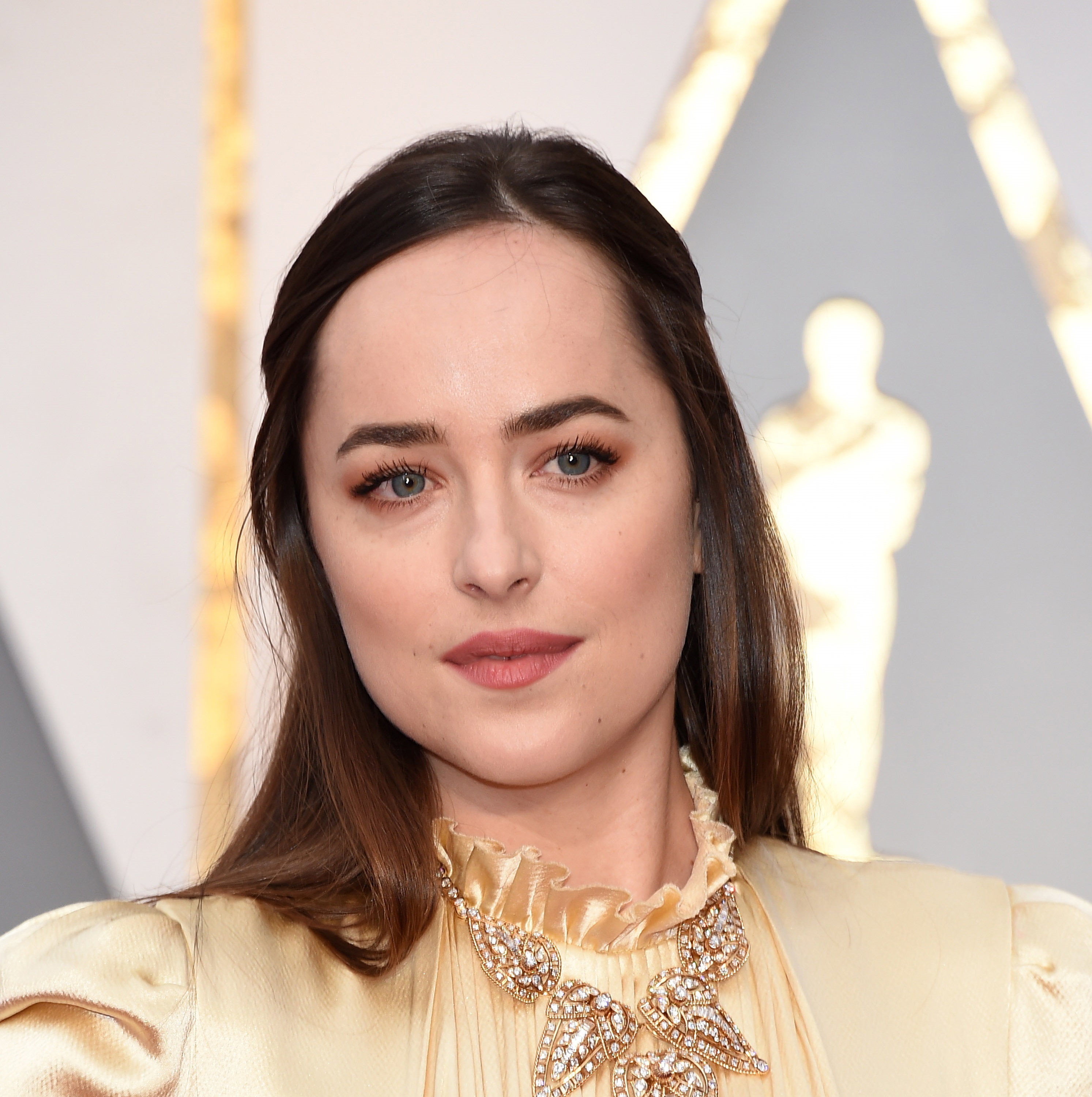 Dakota Johnson pozuje w złotej sukni na czerwonym dywanie podczas rozdania Oscarów 2017