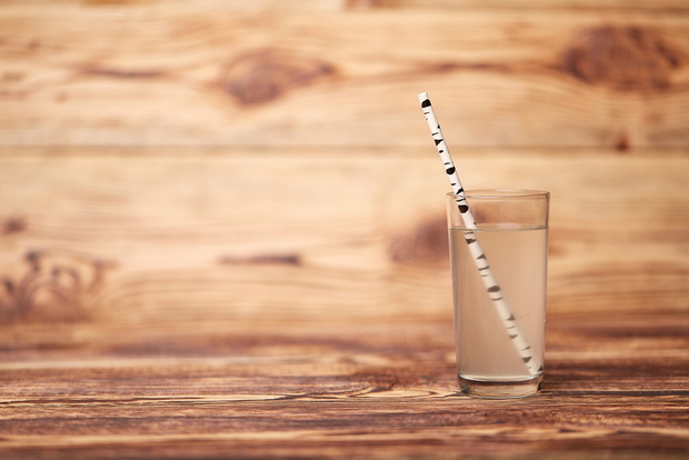 the birch juice on wooden background with straw
