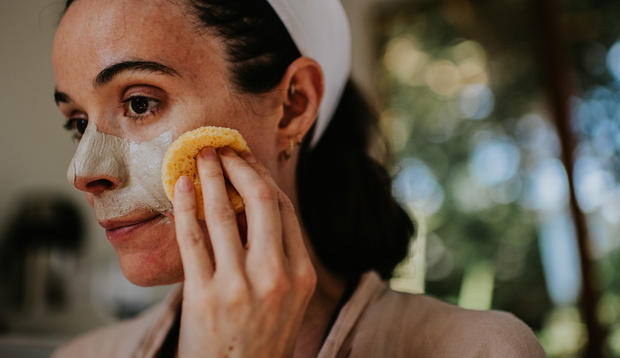 A woman removes a face mask with a small sponge