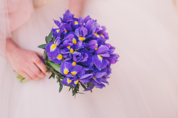 Closeup of a bride holding a bouquet of iris flowers in her hands