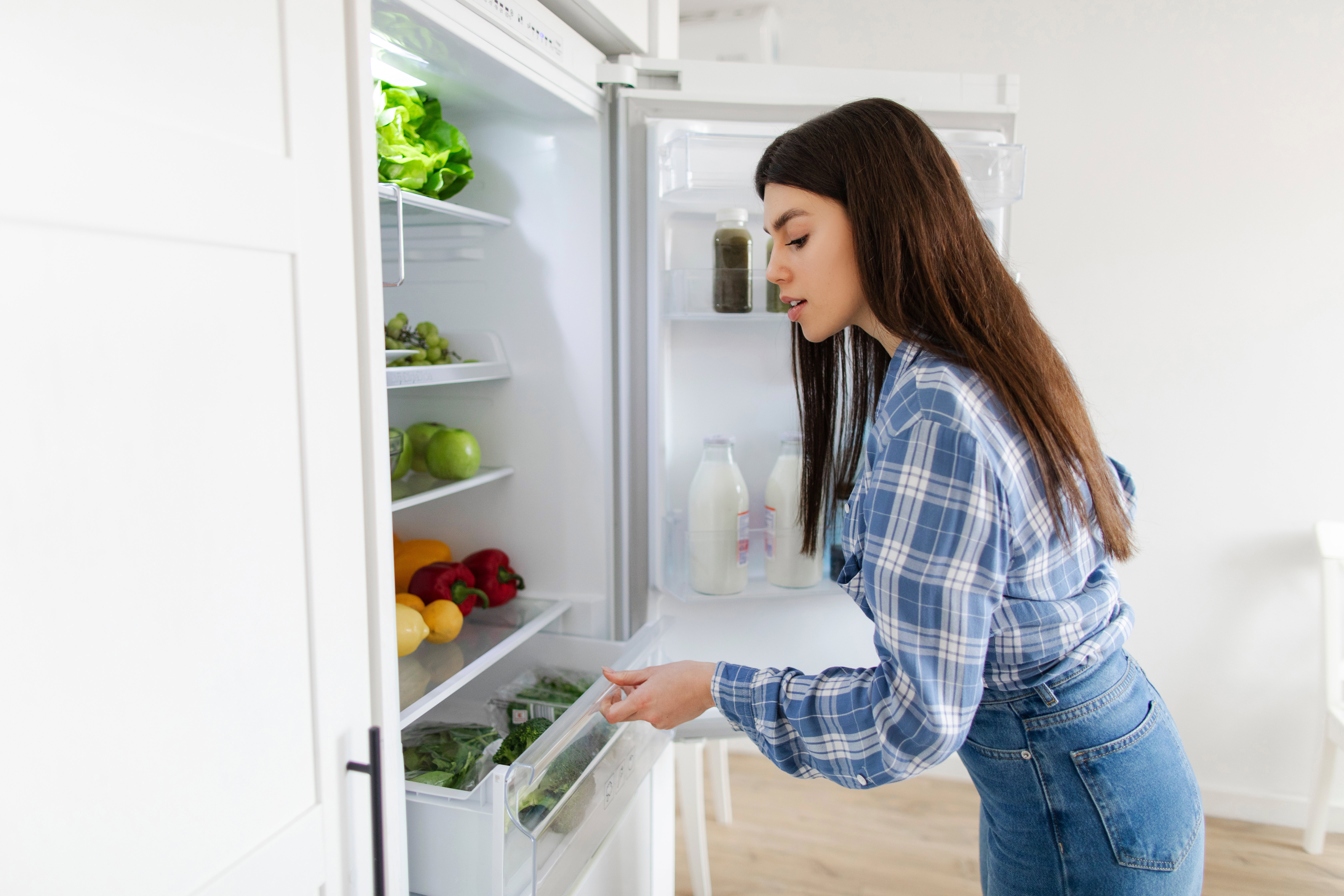 Young woman searching food vegetables, opening refrigerator and planning what to cook for dinner. Meal preparation for dieting