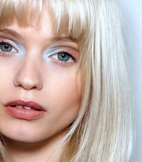 Dziewczny a zbardzo jasnymi blond włosami i niebieskim makijażem