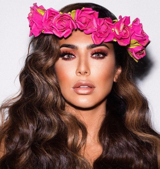 Huda Kattan z wiankiem z różowych kwiatów we włosach