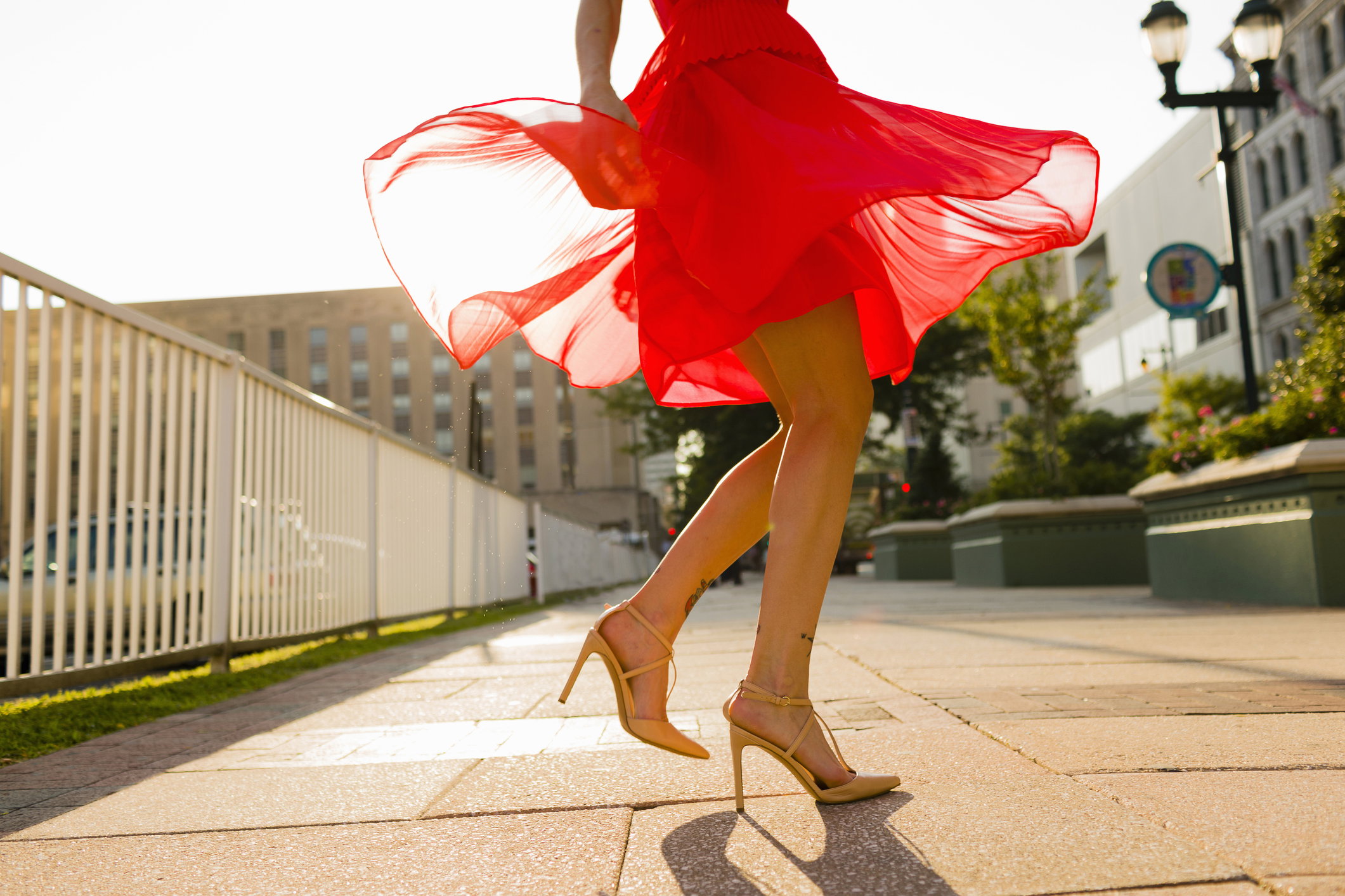 Waist down view of young woman twirling whilst wearing red dress