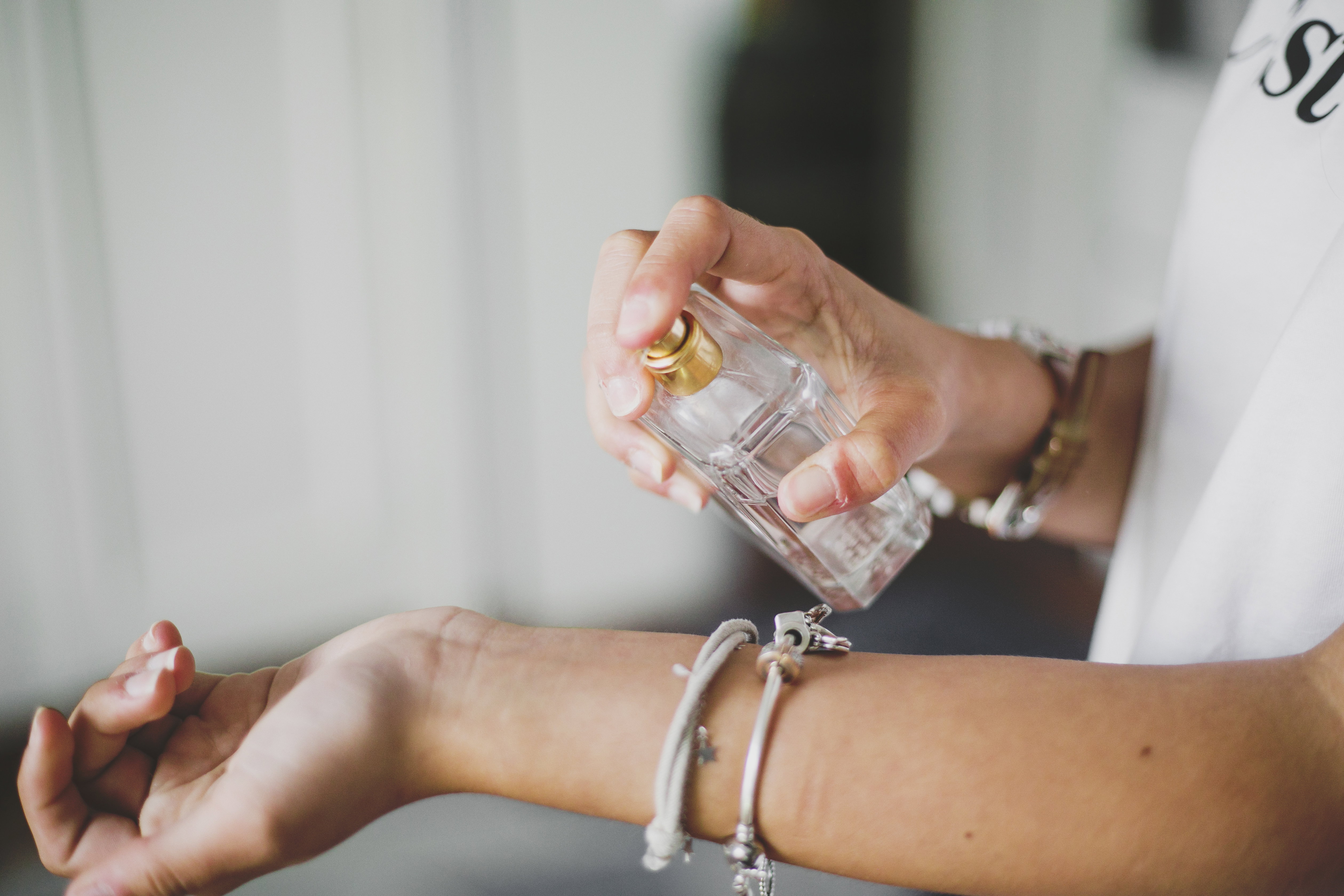 closeup woman spraying perfume on wrist