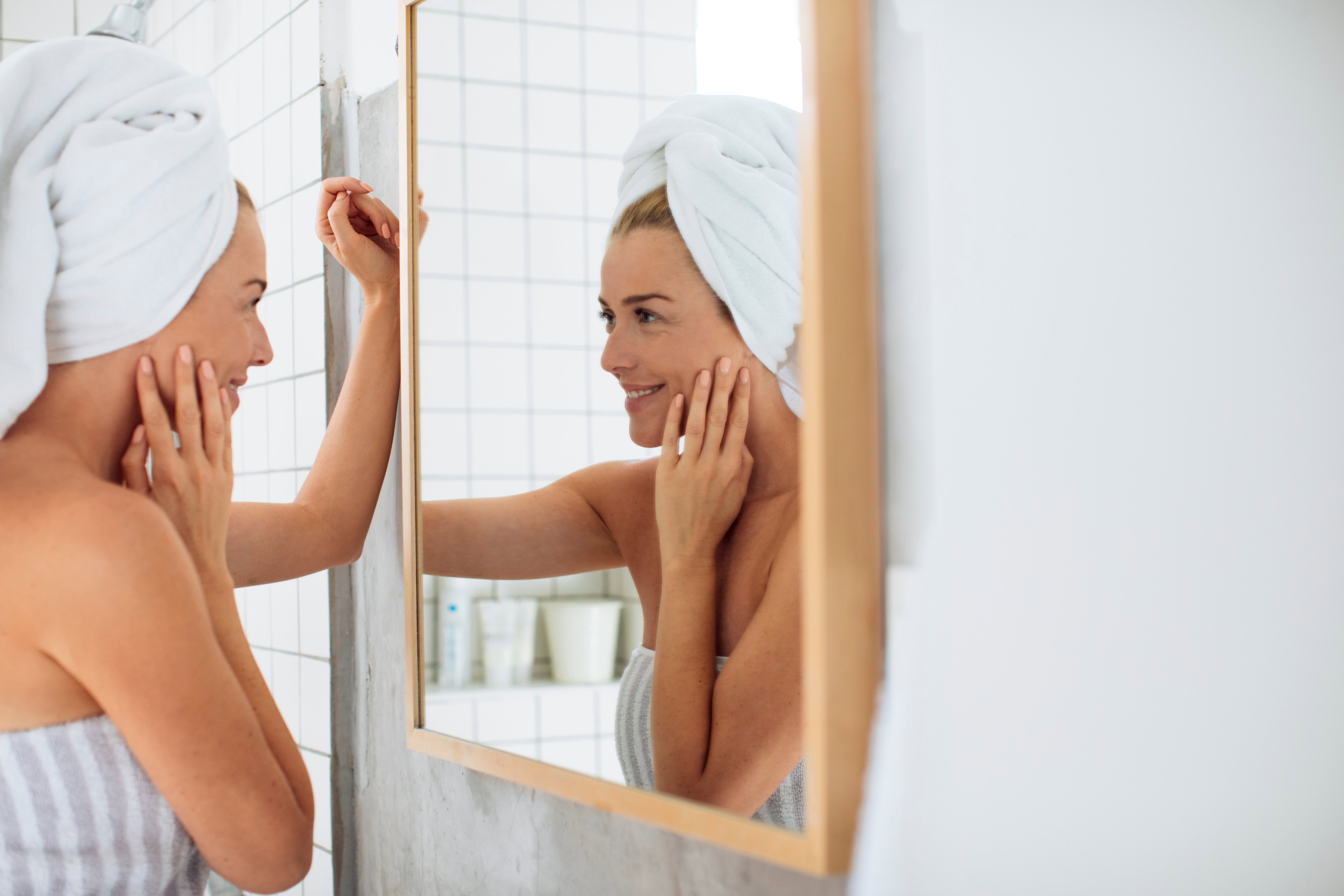 Woman Looking Herself in Bathroom Mirror