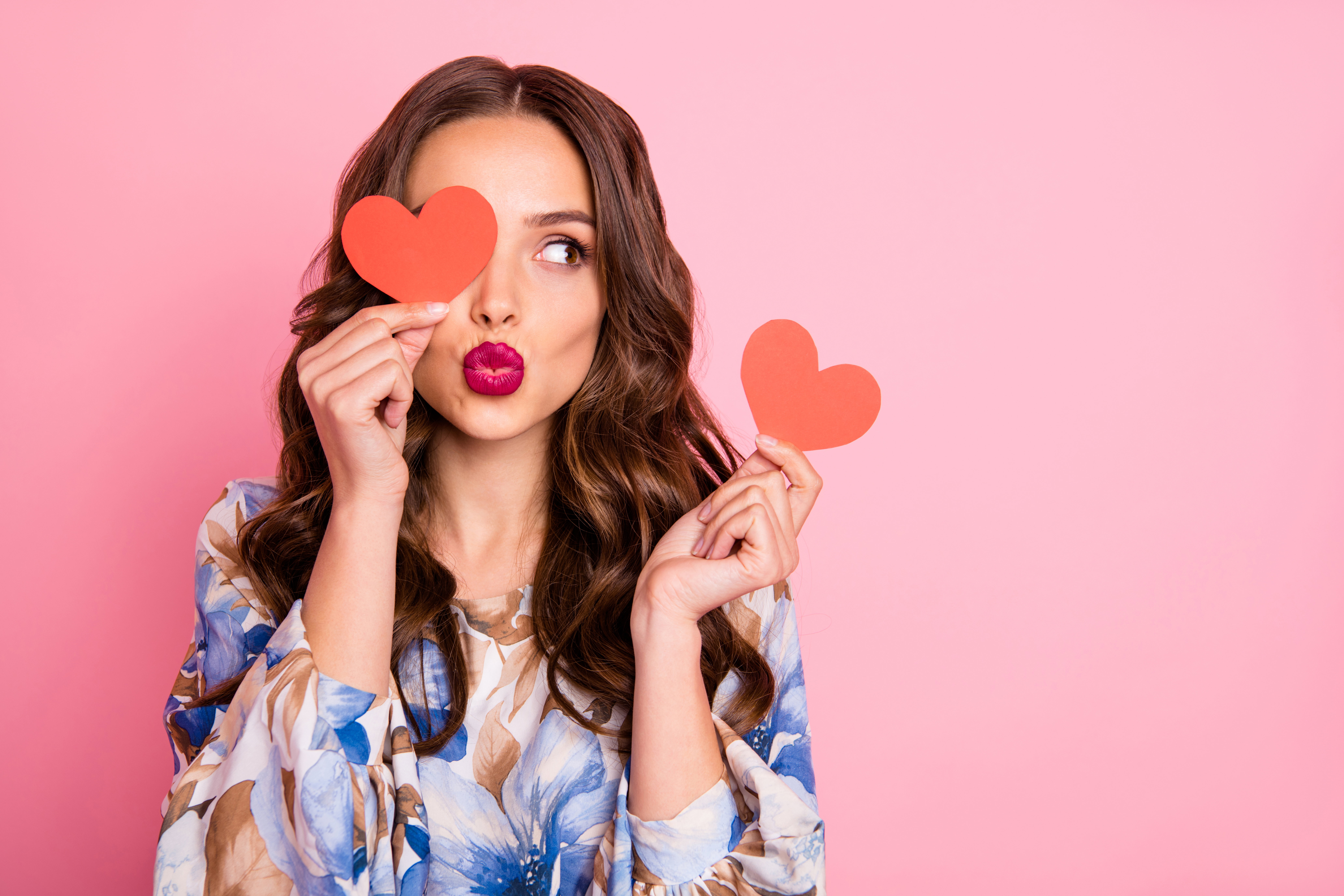 Close-up portrait of her she nice-looking attractive lovely coquettish cheerful cheery wavy-haired girl holding in hands two small little heart sending you kiss isolated over pink pastel background