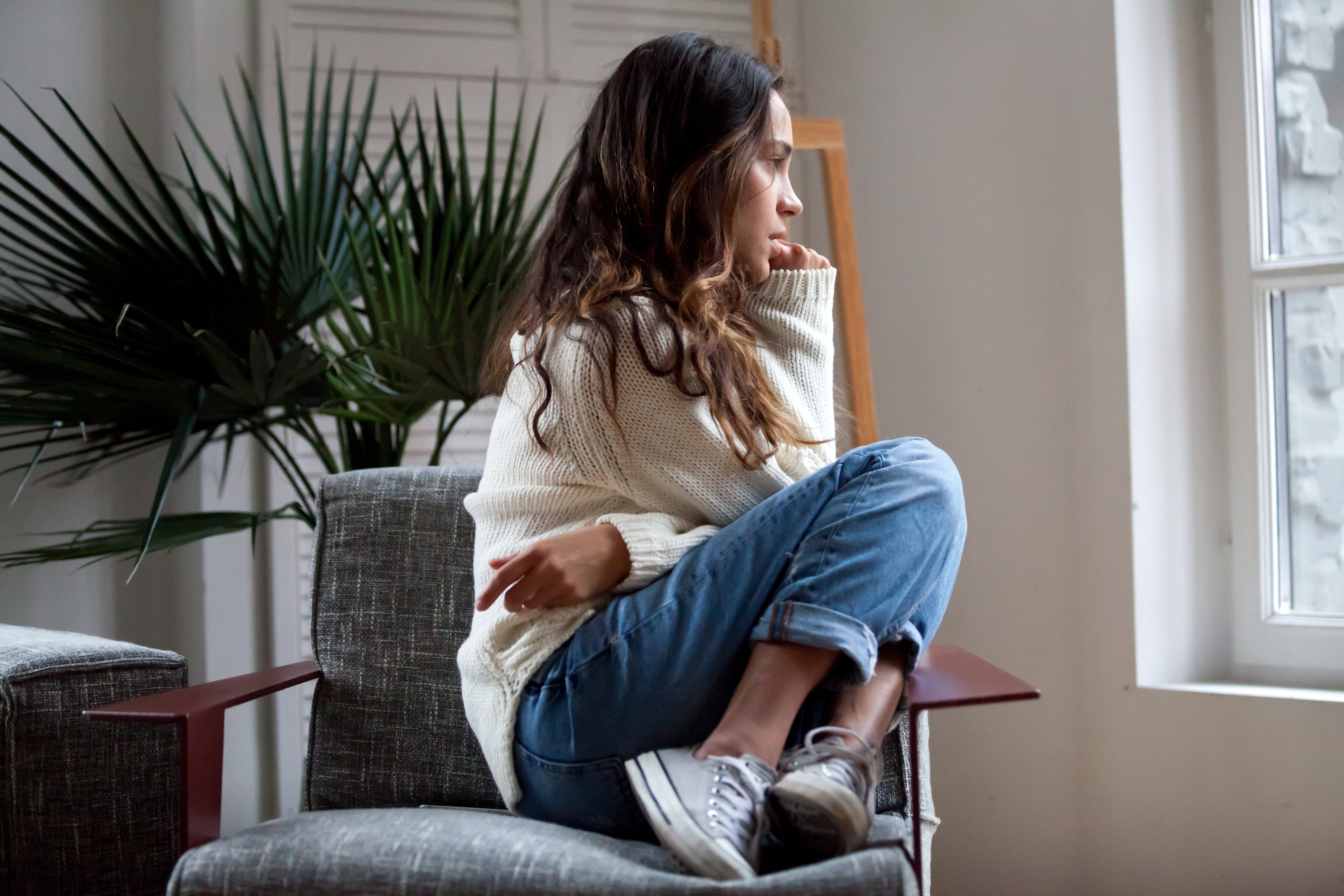 Sad thoughtful girl sitting on chair feeling depressed or lonely